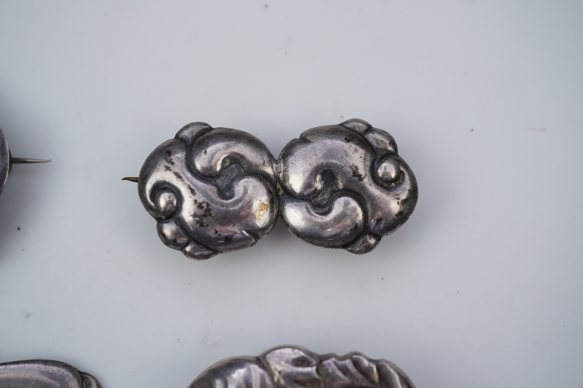 An Arts & Crafts silver slide and three silver brooches, probably Denmark, first half 20th century